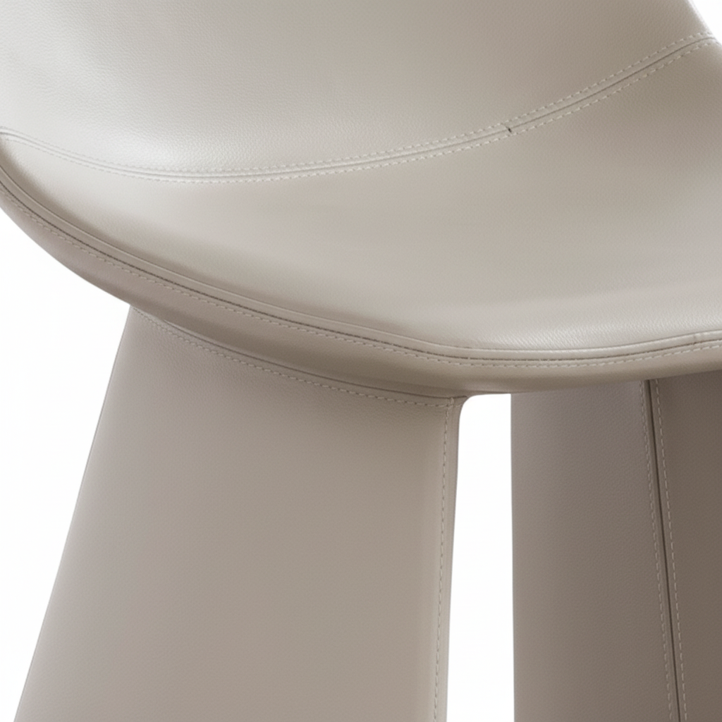 Close-up of the greige leather surface texture and seam detail of the Lama Dining Chair